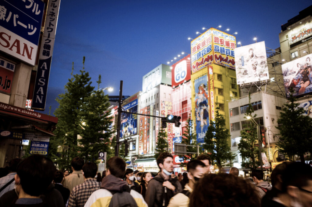 Gaten Akihabara i Tokyo med mennesker og glitrende bysilhuett.