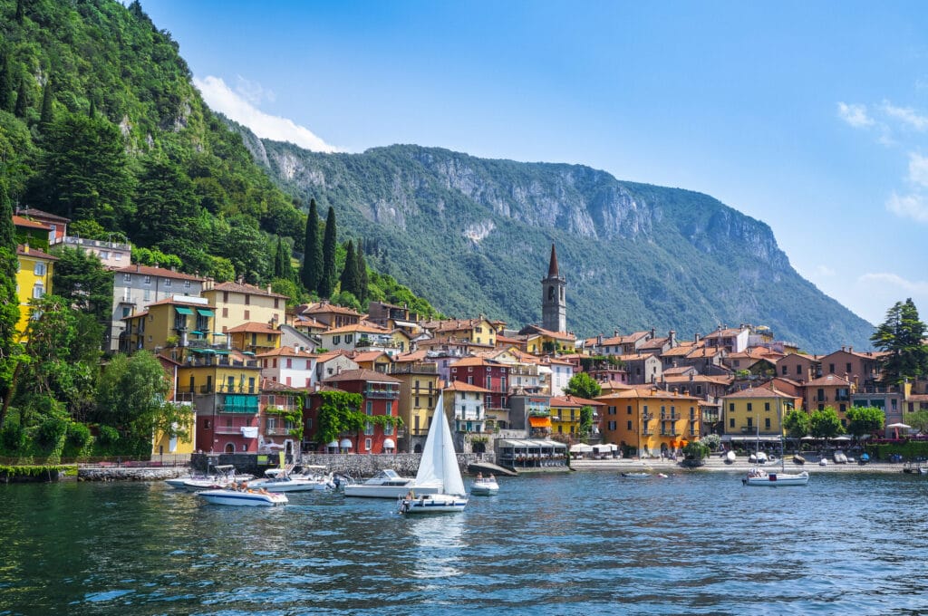 Lake Como med fargerike hus, båt og elv. 