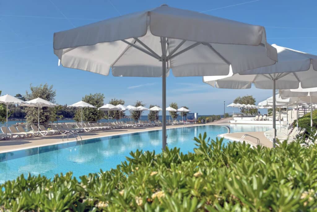 Hotell med hvite parasoller og et basseng.