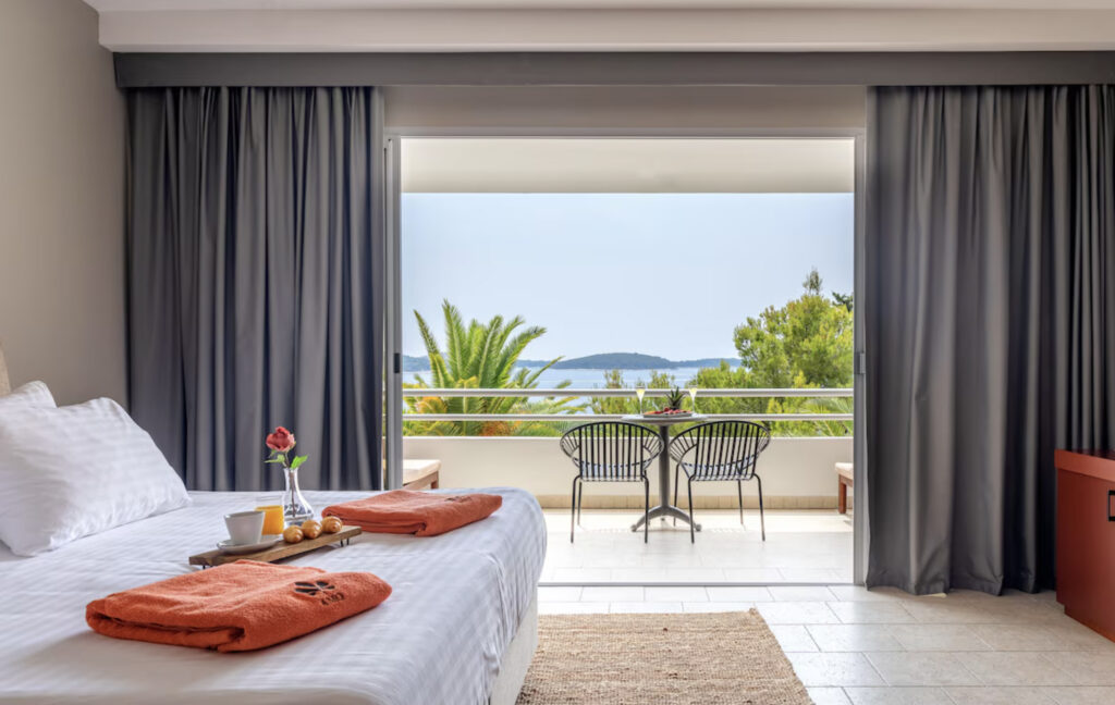 Podstine Hotel med dobbeltseng og balkongutsikt over vannet.