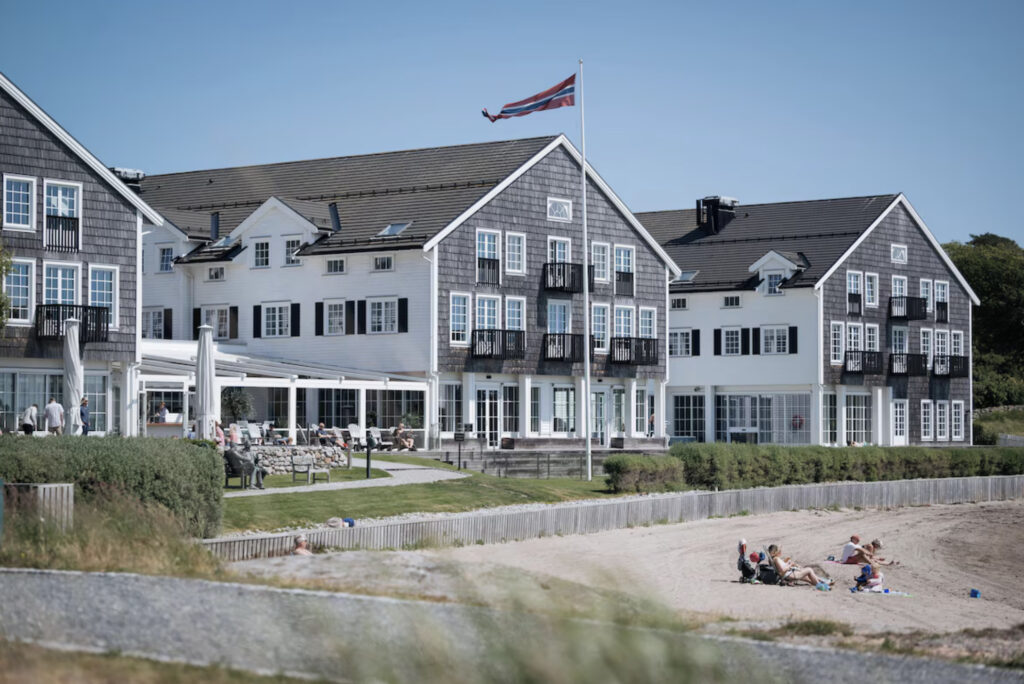 Støtvig Hotel med sandstrand og mennsker som sitter utenfor hotellet. 