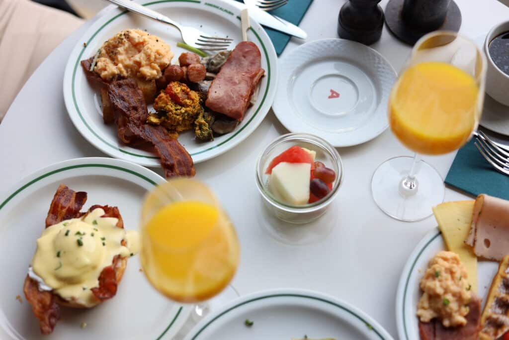 Frokostbord på Amerikalinjen i Oslo. Det er tallerkener med bacon, egg, egg benedict og vafler, frukt, appelsinjuice. 