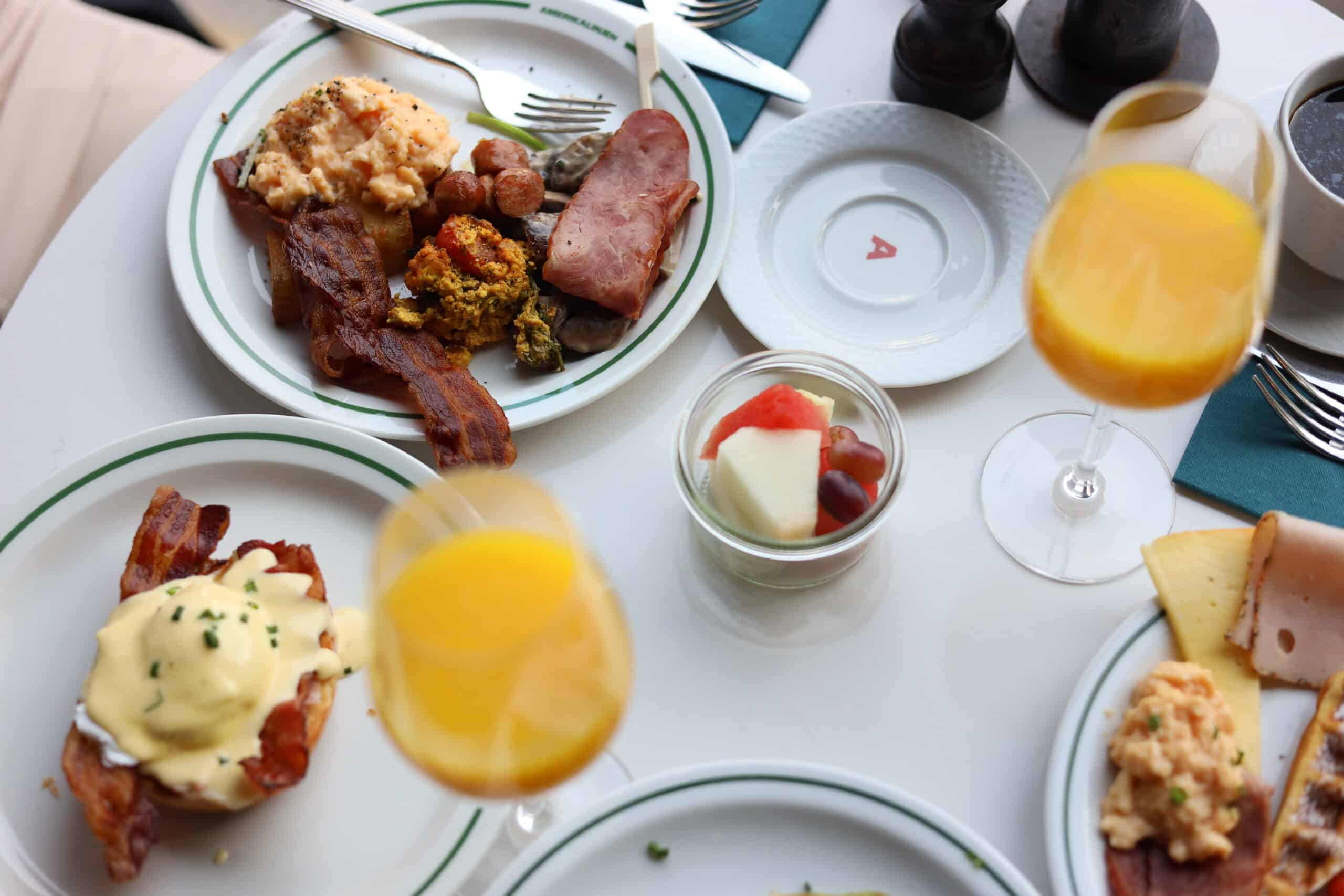 Frokostbord på Amerikalinjen. Bacon, appelsinjuce, bagels med laks, egg benedict, frukt og kaffe.
