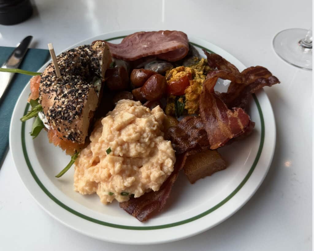 Tallerken med bacon, egg, bagels og tomater. 