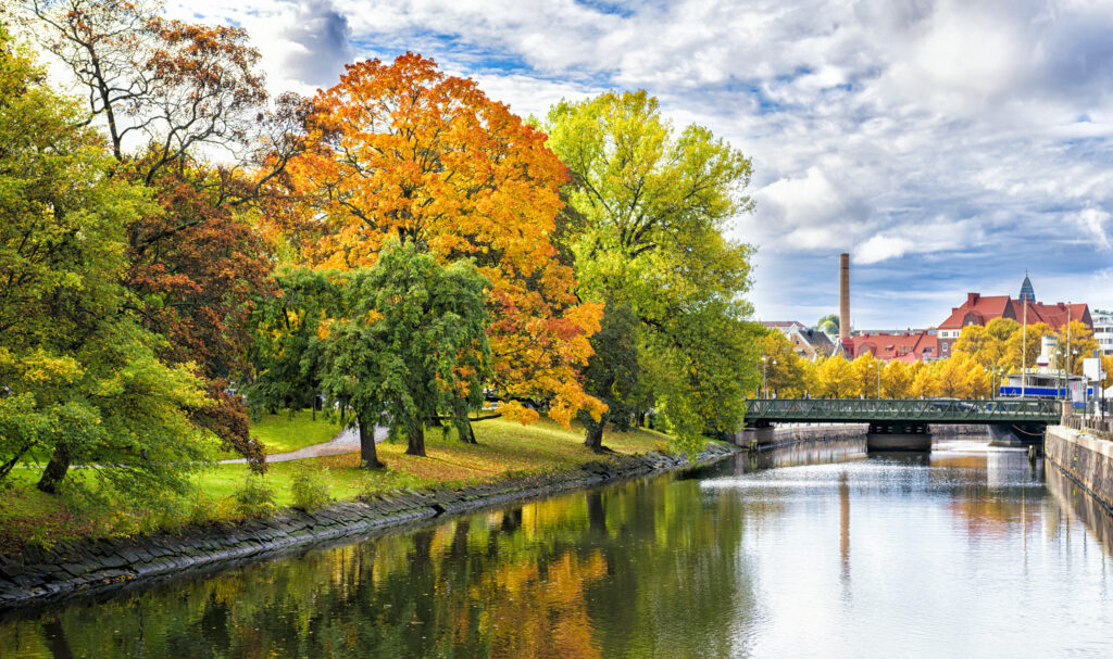Høsttrær, kanal, vann og hus. 