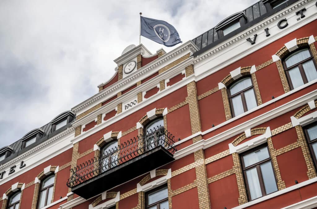 Hotellfasade med brune vegger, flagg på topp.
