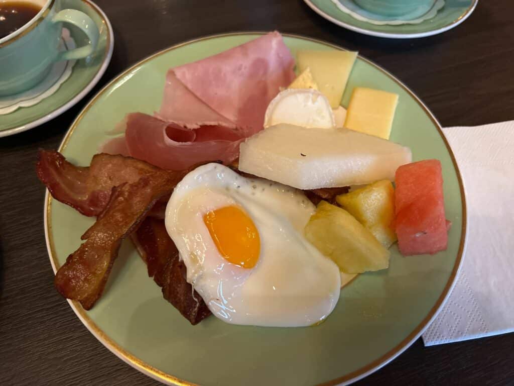 Egg, bacon og frukt på fat. 
