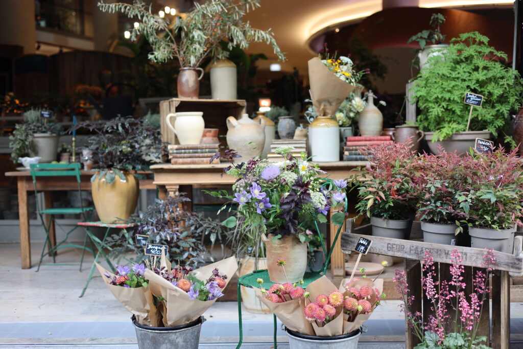 Utenfor døra ser man blomster og interiør fra Frankrike.