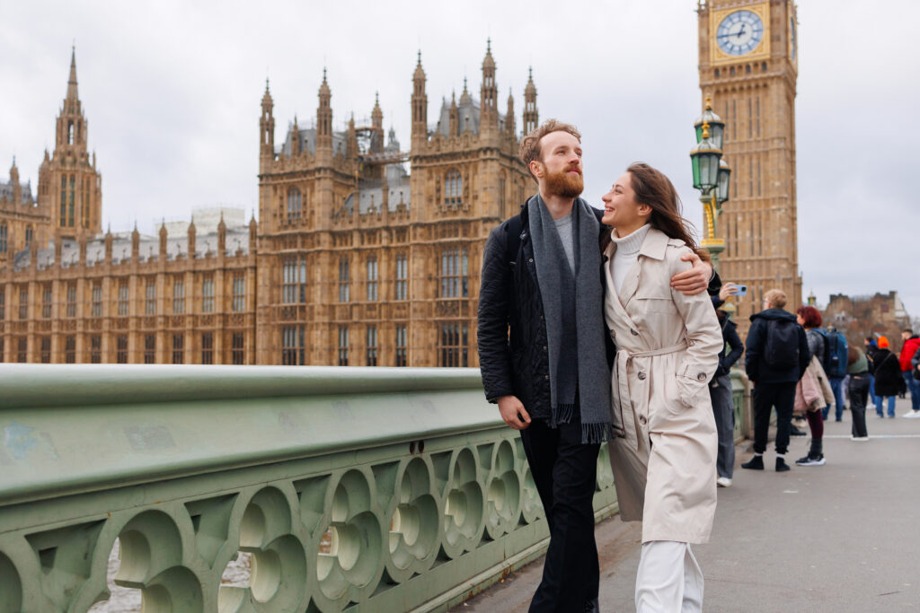 Lykkelig ungt par av reisende som går over Westminster Bridge med Big Ben i bakgrunnen.