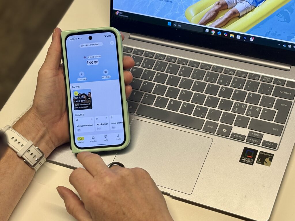 mann holder iphone i hånden over tastaturet på en mac
