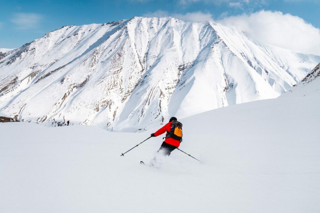 Gudauri skiresort med person som står på ski og har snødekt fjell-landskap foran seg.