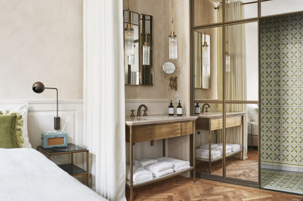 Hotellrom i Wien med seng, bad og vask med speil. 