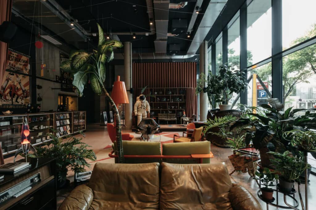 Hotell i Wien med lobby, mange spennende og retro interiør. Skinnsofa, astronaut-kostyme-statue og mange planter. 
