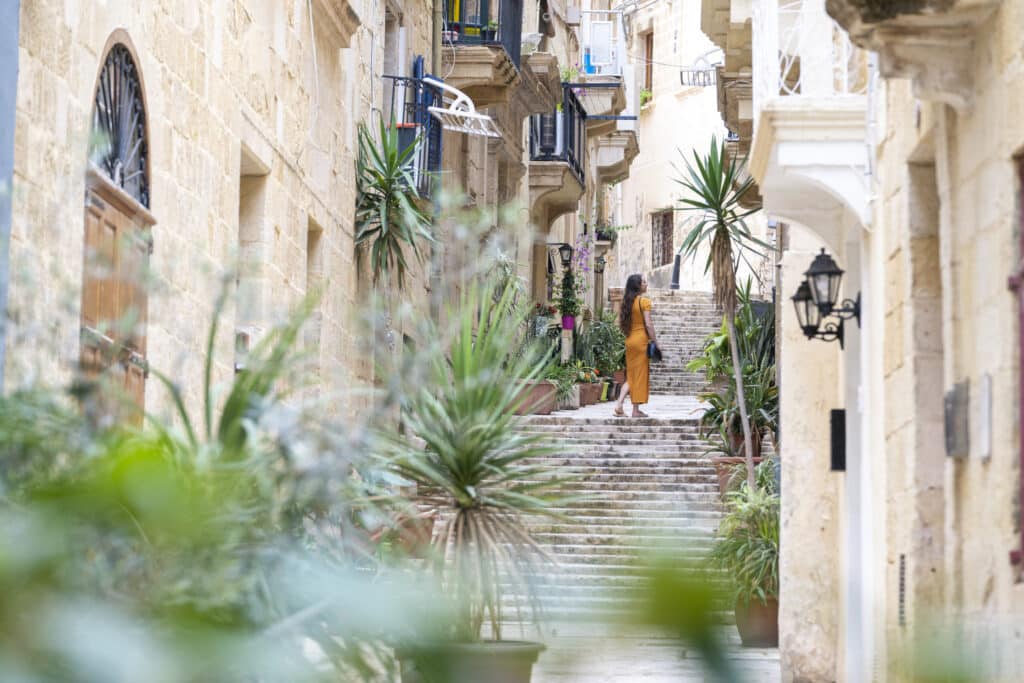 Kvinne står i trapper i byen valletta på Malta