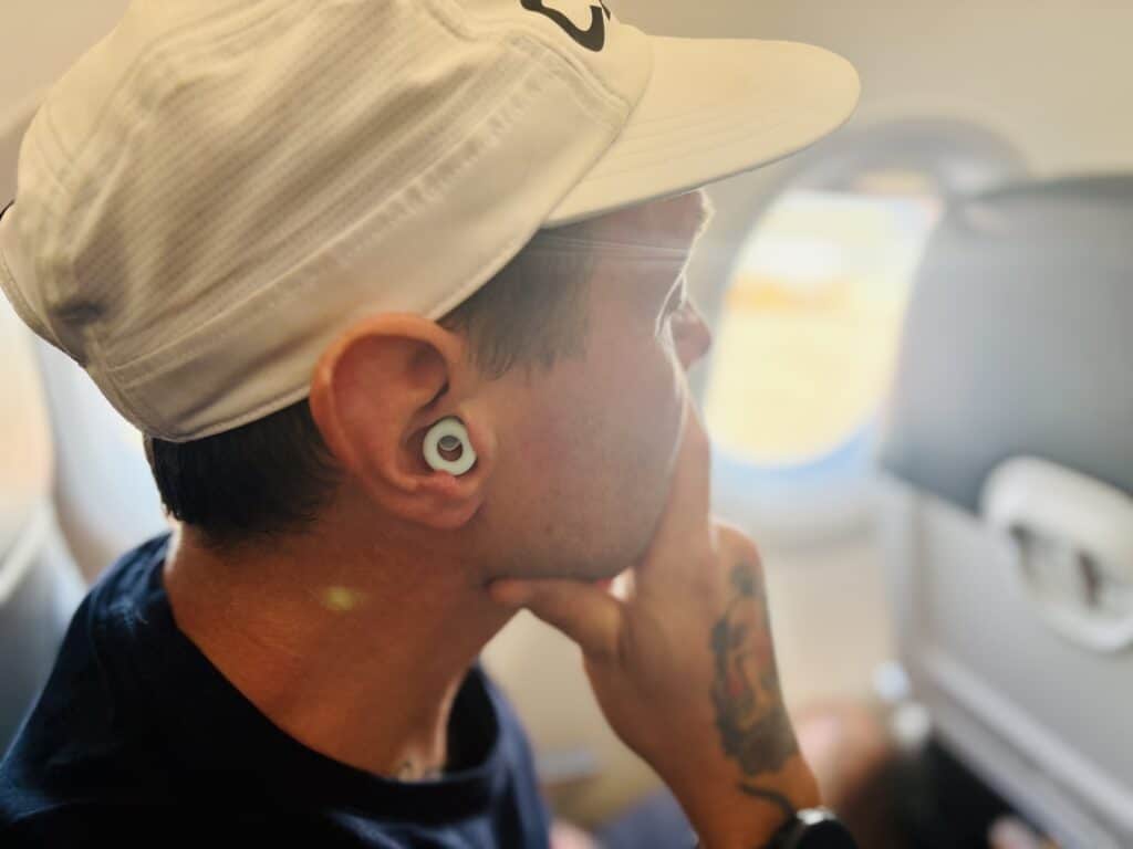mann med ørepropper i øret på fly